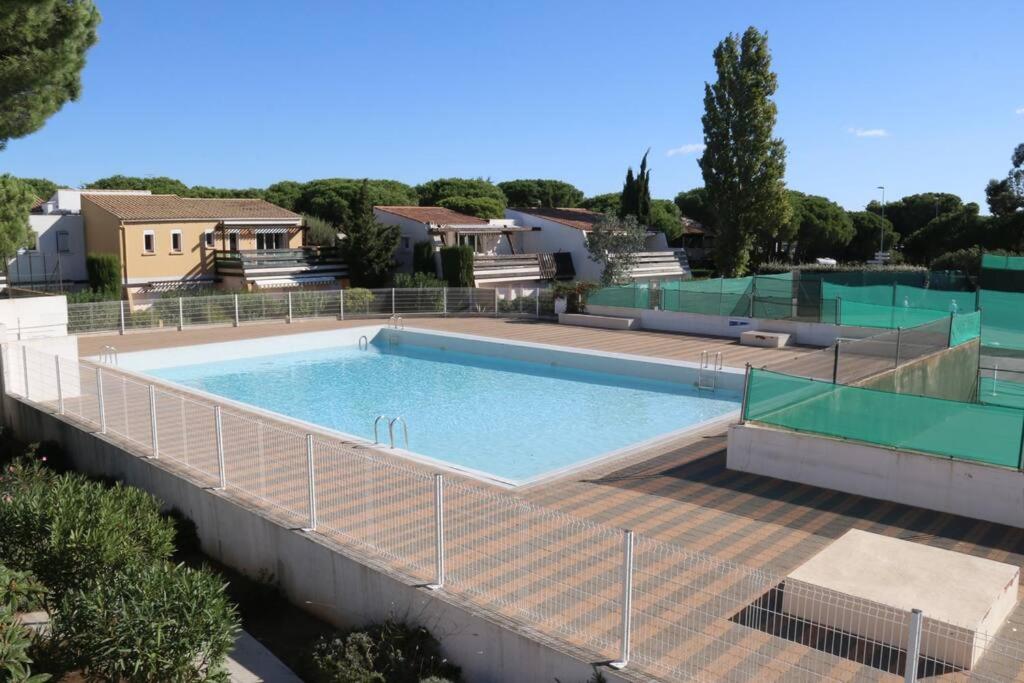 une grande piscine entourée d'une clôture. dans l'établissement Appart 1403, Tennis village, au Cap d'Agde