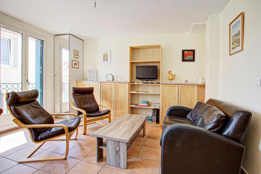 a living room with a couch and chairs and a tv at Obelisque 1B - duplex climatisé in Port-Vendres