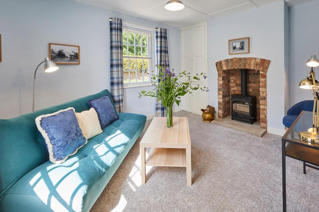 a living room with a blue couch and a fireplace at Host & Stay - Park View in Brafferton