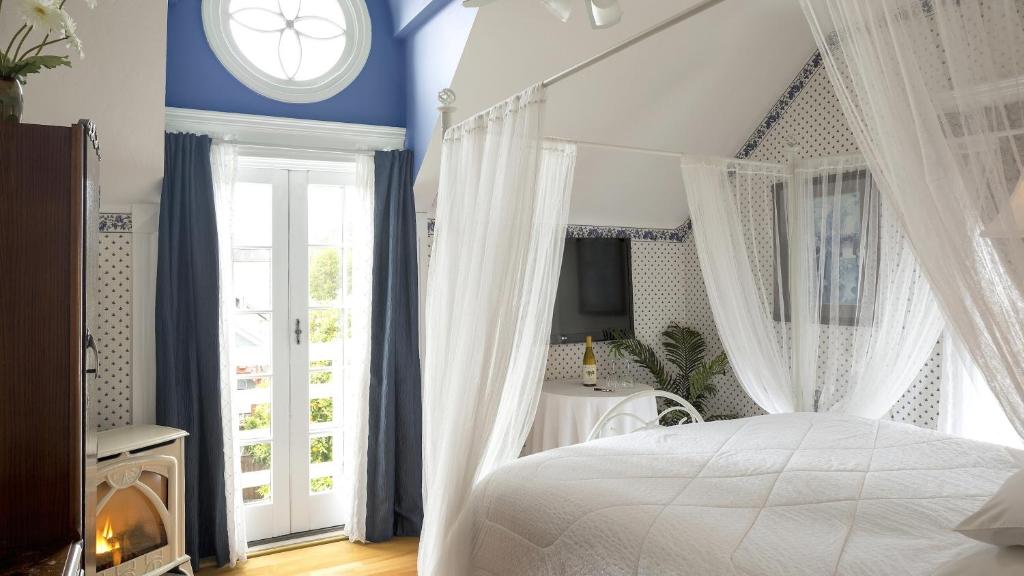 una camera da letto con un letto bianco con tende e una finestra di Cabernet House, an Old World Inn a Napa