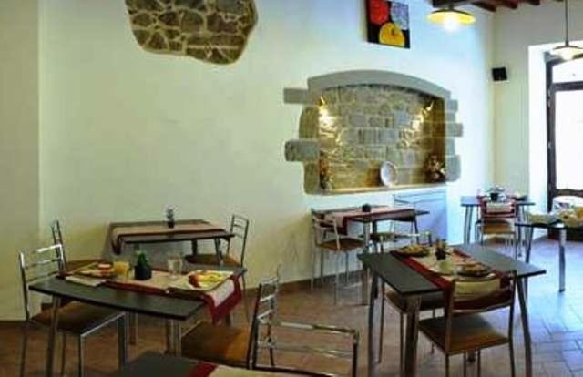 ein Esszimmer mit Tischen, Stühlen und einem Kamin in der Unterkunft Bed & Breakfast Viziottavo in Castiglion Fiorentino
