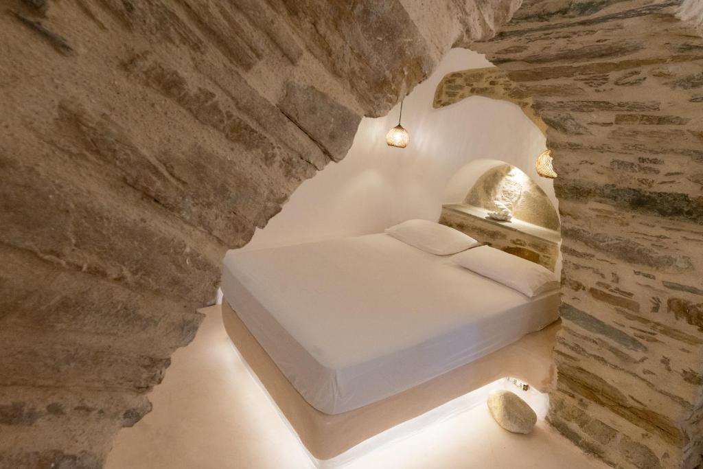 a bedroom with a bed inside of a stone wall at Cave Dame in Mési