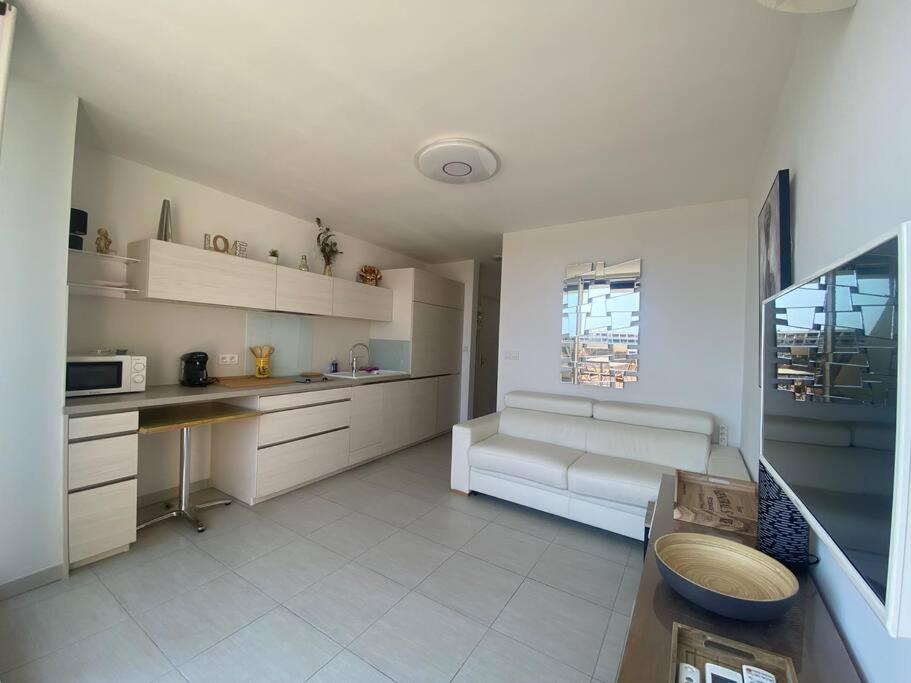 - une cuisine blanche avec un canapé et une table dans l'établissement Appart 408, Héliopolis K au village naturiste, au Cap d'Agde