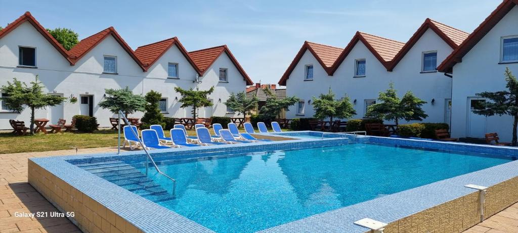 a swimming pool with lounge chairs in front of a building at Aqua Fun Domki z Basenem in Darłowo