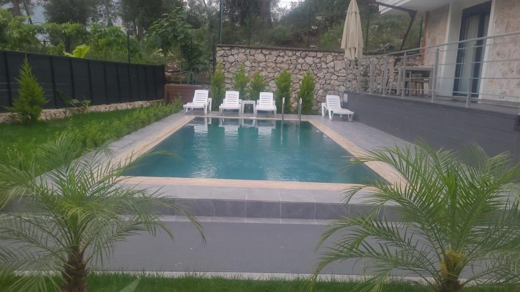 a swimming pool with white chairs in a backyard at Silyan Villas in Antalya
