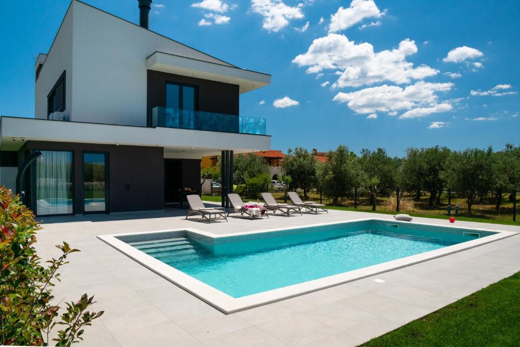 a villa with a swimming pool in front of a house at Arestea in Vodnjan