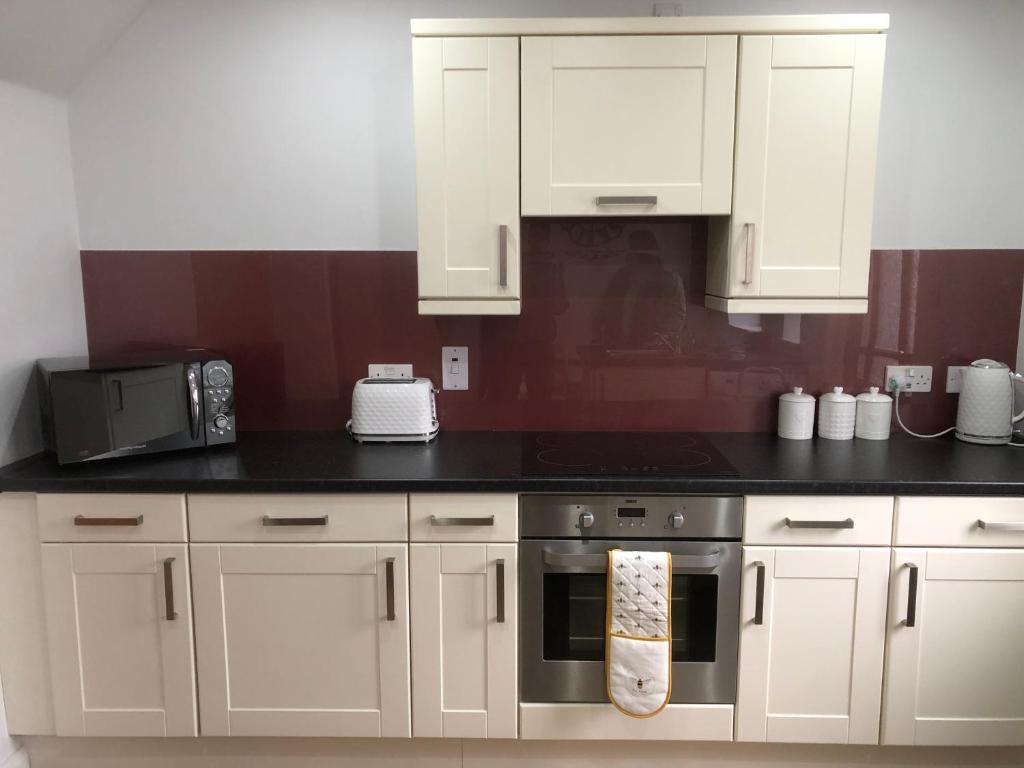 a kitchen with white cabinets and a stove top oven at Moray View, Macduff, Aberdeenshire. in Macduff