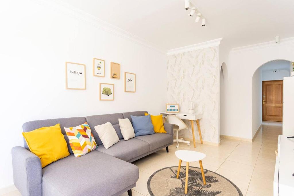 sala de estar con sofá gris y almohadas amarillas en Amplio y cómodo apartamento en Callao Salvaje., en Callao Salvaje