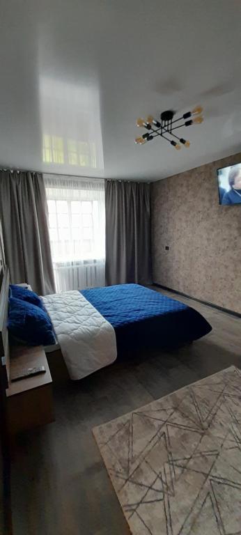 a bedroom with a blue bed and a window at аппартаменты Ауезова 238 in Kokshetau