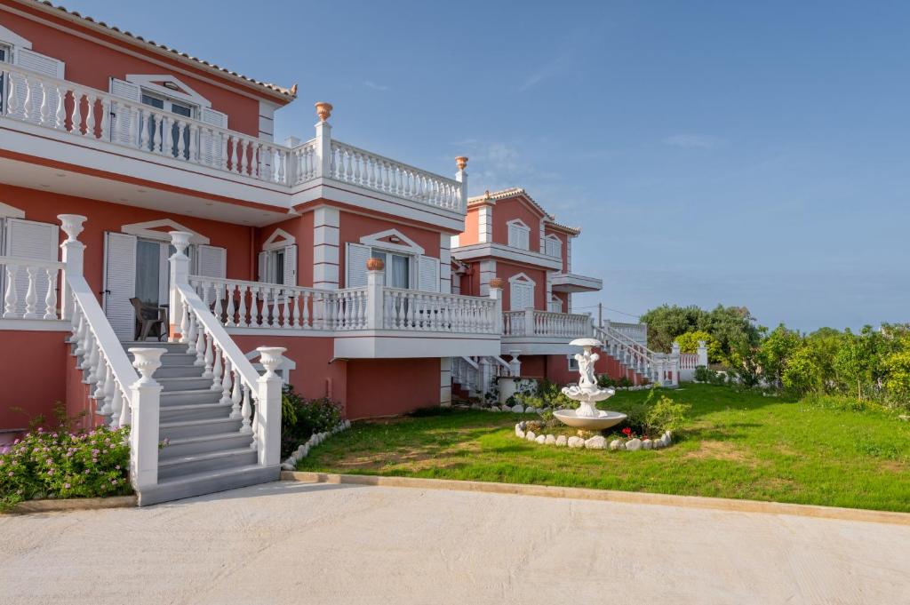 a large pink house with a fountain in the yard at Five Stars Villa in Skala Kefalonias