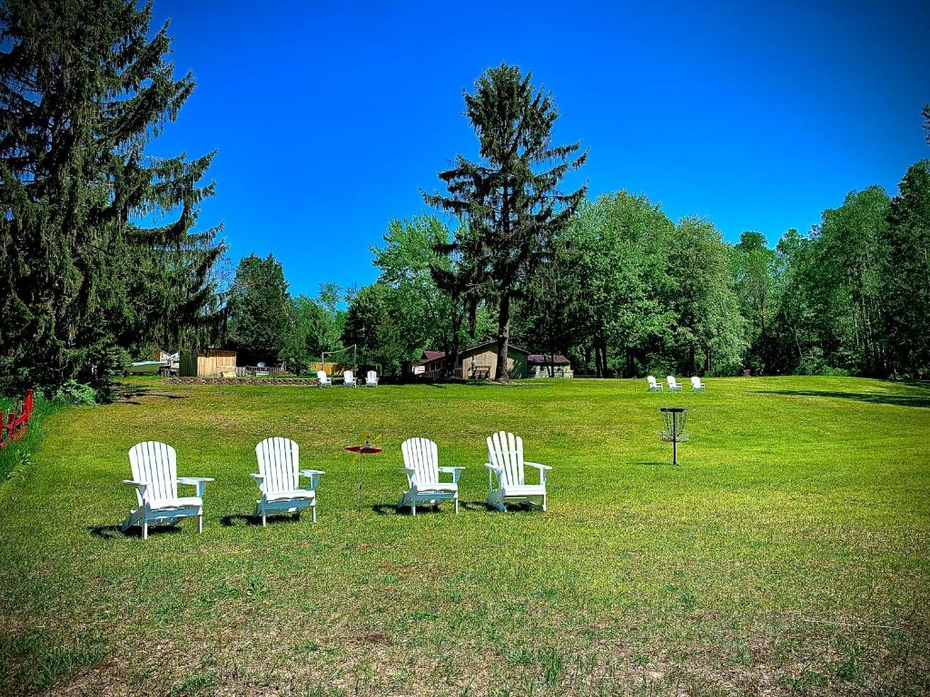 a group of white chairs sitting in a field at Benzonia Rustic Resort in Benzonia