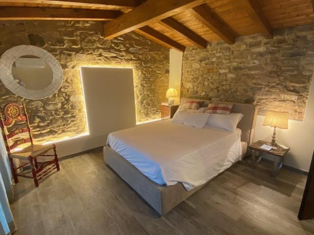 ein Schlafzimmer mit einem Bett und einer Steinmauer in der Unterkunft Gli Orti dei Doria di dolceacqua in Dolceacqua