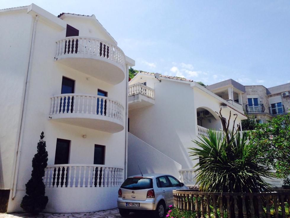 a white house with a car parked in front of it at Apartments Svorcan in Budva