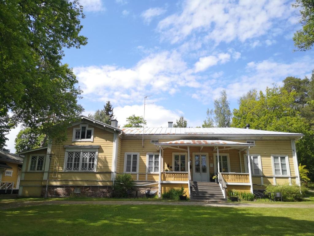 una casa amarilla con porche y césped en Willa Björksten en Lovisa