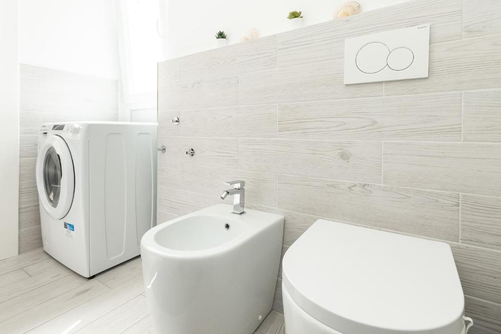 a bathroom with a toilet and a washing machine at Sea Loft Quinto - A due passi dal mare in Genoa