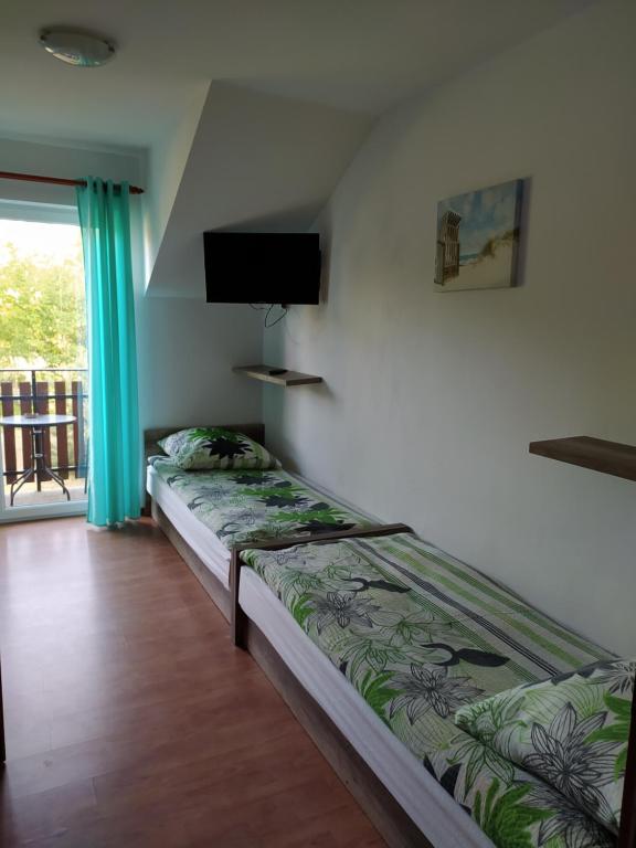 a bedroom with two beds and a flat screen tv at Pokoje Gościnne Ontario Mieroszyno in Jastrzębia Góra