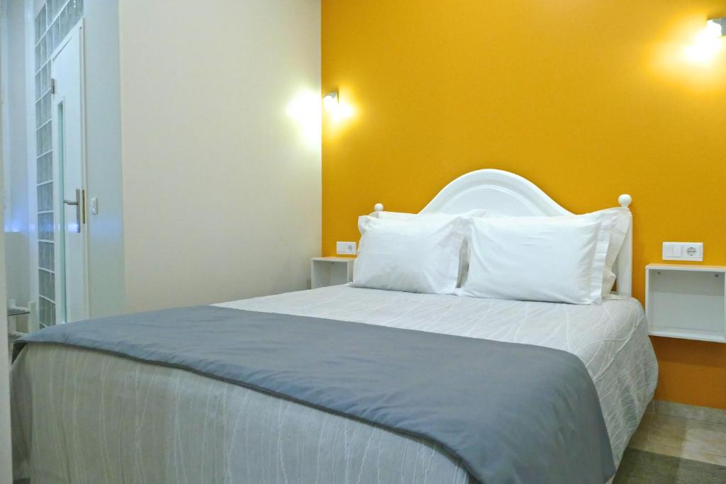 ein Schlafzimmer mit einem großen Bett mit gelber Wand in der Unterkunft Guest House Sao Filipe in Faro