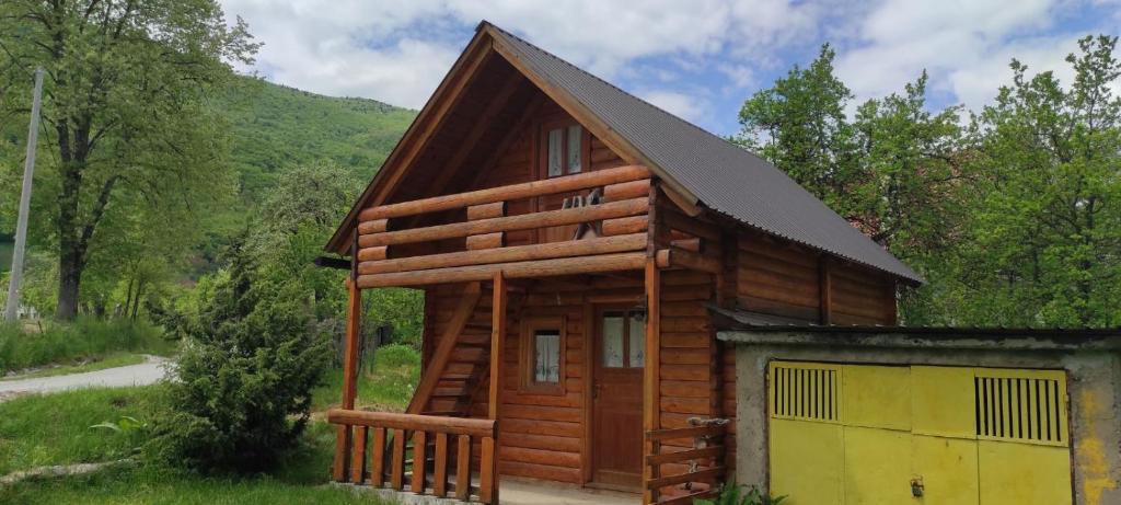a log cabin with a yellow garage in the grass at Velemun brvnara in Plav
