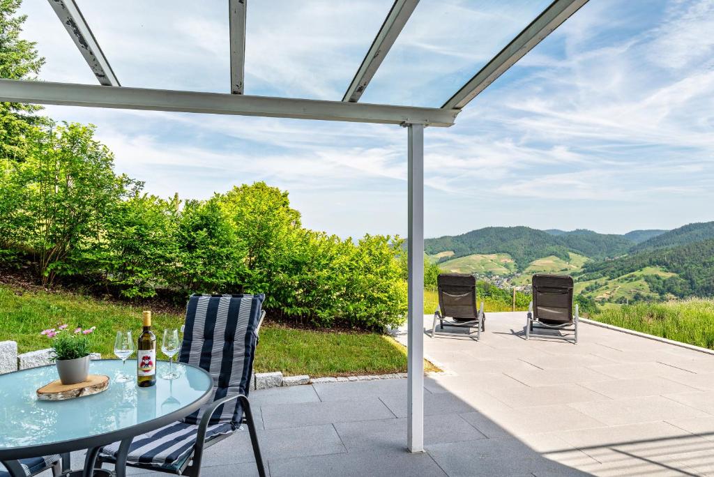 uma mesa e cadeiras num pátio com montanhas ao fundo em Merzel's schöne Aussicht em Bühlertal