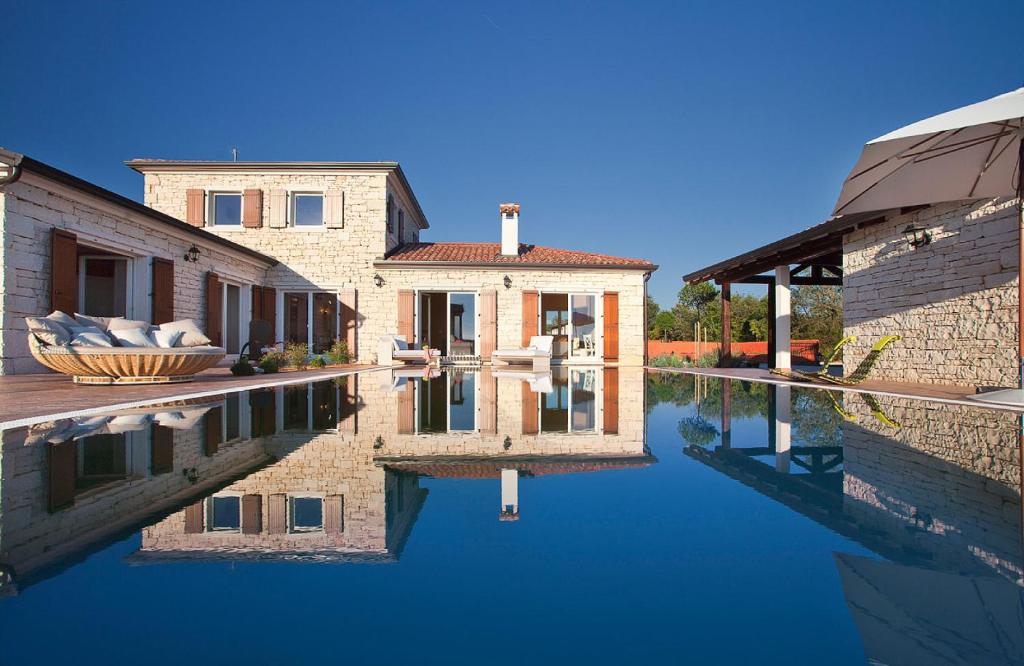 a house with a reflection in a pool of water at White Pearl in Čabrunići