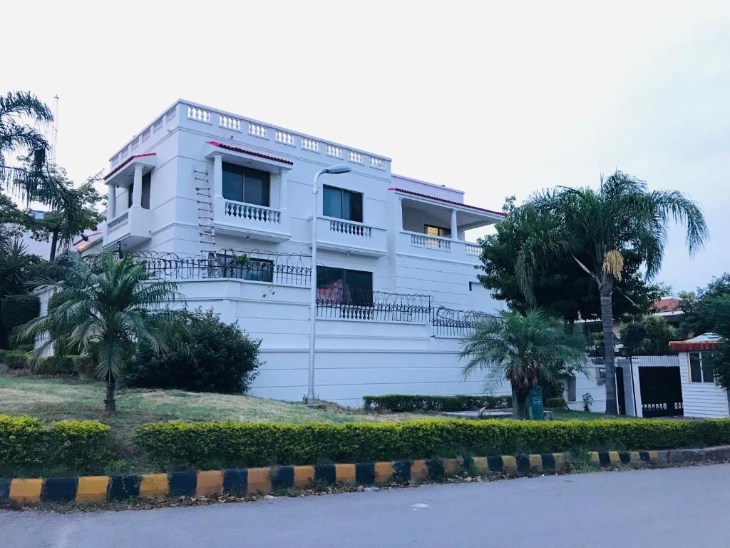 un edificio bianco con palme di fronte di Royal Palace Boutique Hotel a Islamabad