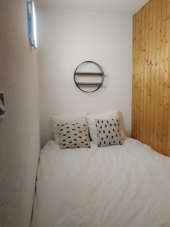a bed with white sheets and pillows in a bedroom at Studio entre lac entre montagnes in Saint-Sauveur