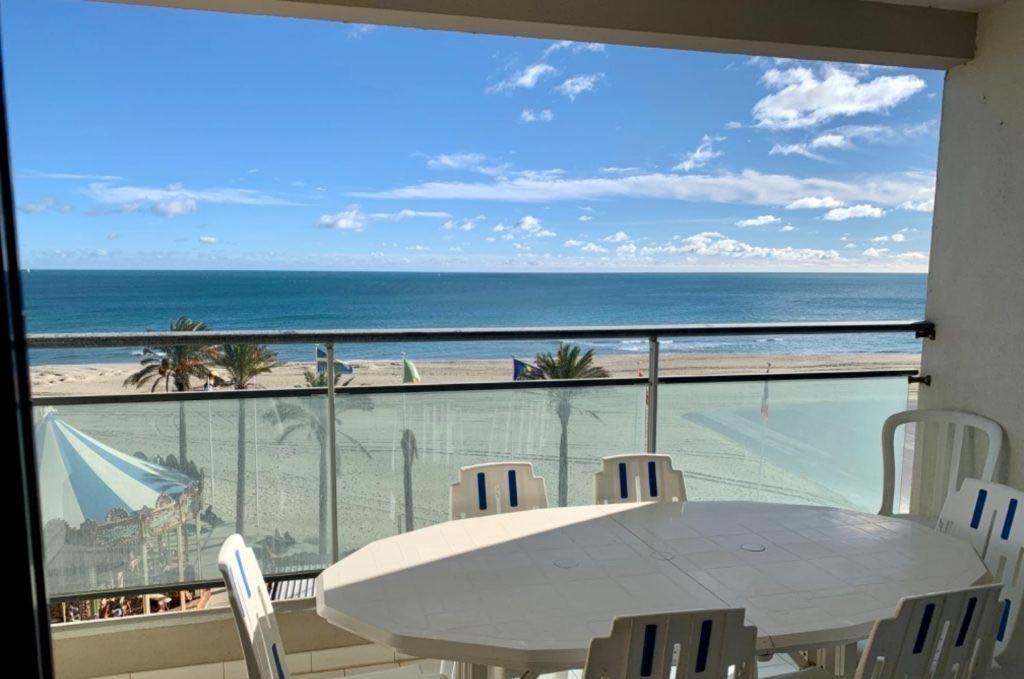 une table et des chaises sur un balcon avec vue sur la plage dans l'établissement Le Bel Air, à Canet