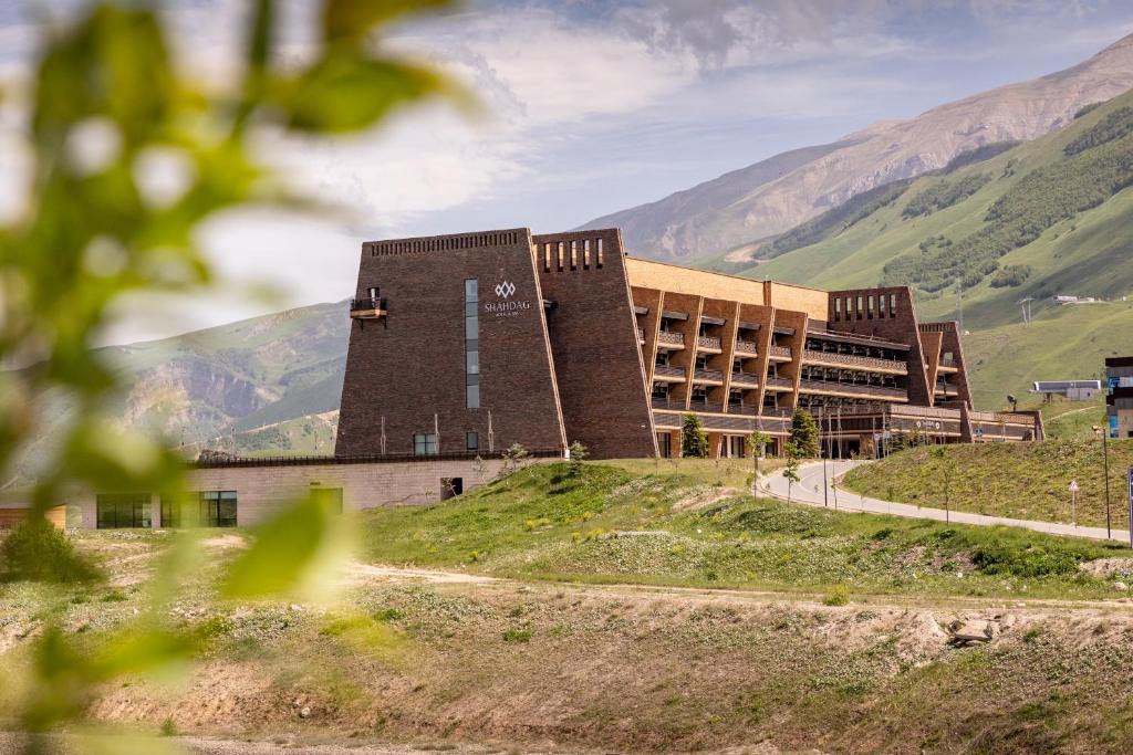 a building on a hill with mountains in the background at Shahdag Hotel & Spa in Shahdag