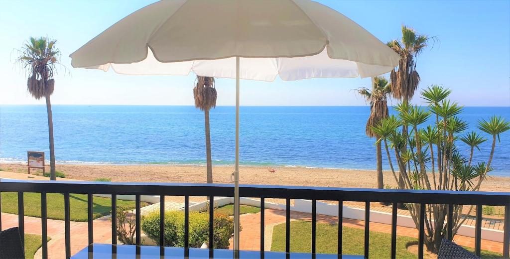 a view of the ocean from a balcony with an umbrella at Sea Front Beach house Micaela G in Marbella