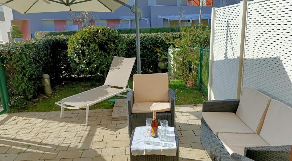 patio con divano, sedia e ombrellone di Grazioso a Bibione