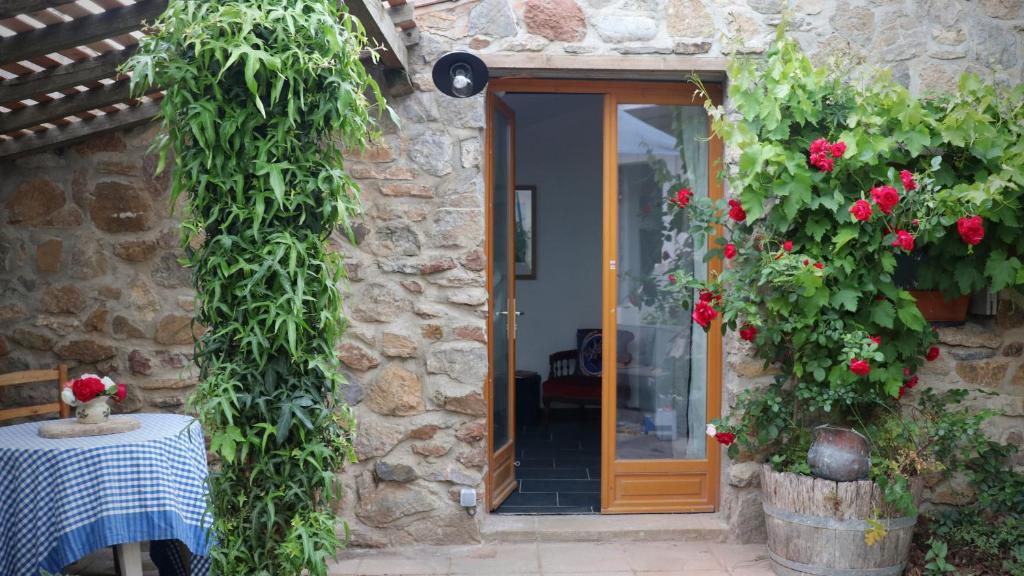 une entrée d'une maison en pierre avec une table et des fleurs dans l'établissement Esclarmonde 18, à Cascastel-des-Corbières