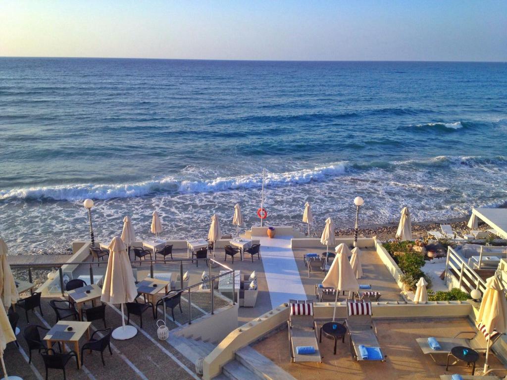 a view of the beach with chairs and umbrellas at Filoxenia Beach Hotel in Rethymno