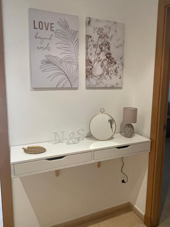 a dressing table with a mirror and pictures on the wall at Apartamento N&S Carolinas in Vilagarcia de Arousa