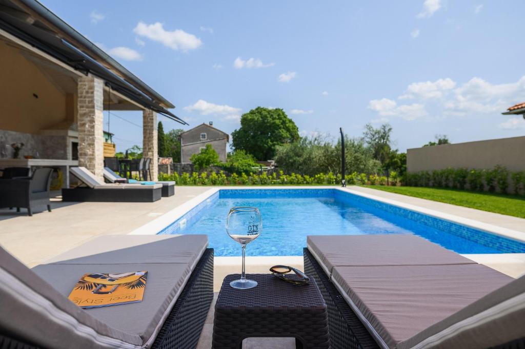 uma piscina com uma mesa e um copo de vinho em Villa Istra Maružini by Solis Porec em Maružini