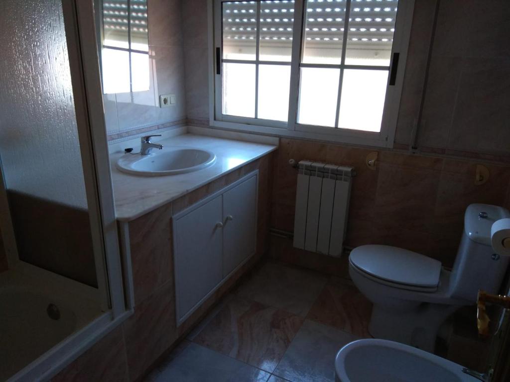 a bathroom with a sink and a toilet and windows at Apartamento O CASAL in O Grove