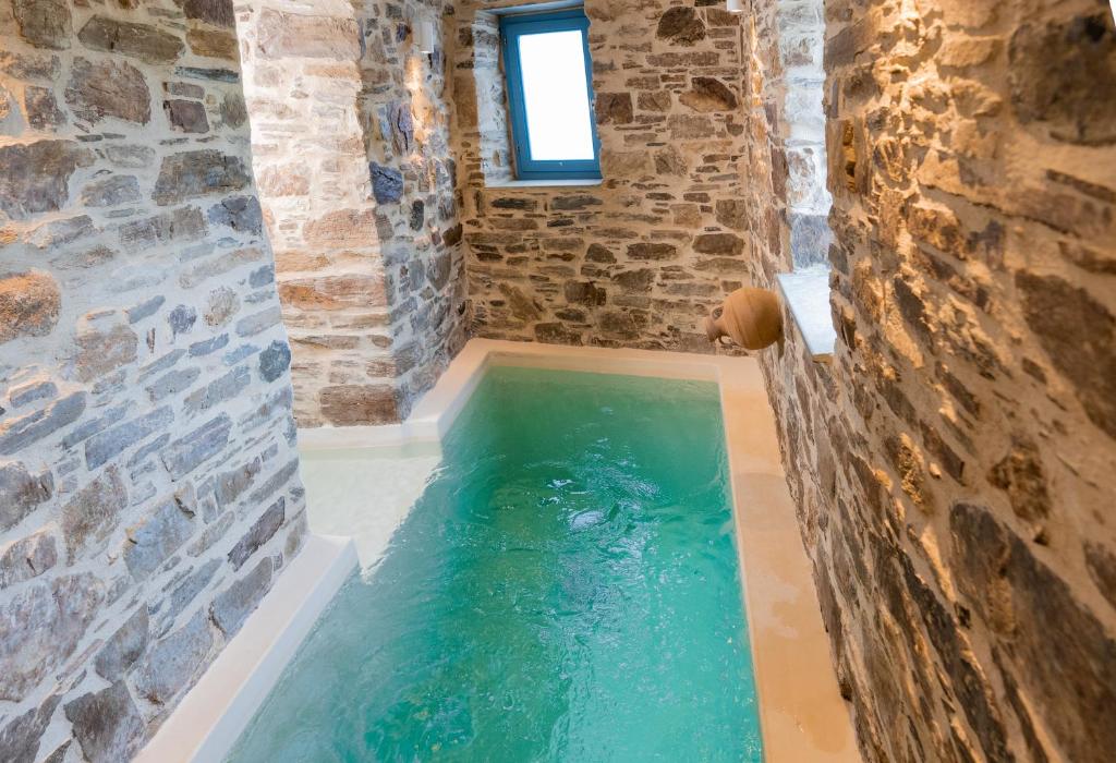 a pool of water in a room with a stone wall at Private Pool Dame in Mési