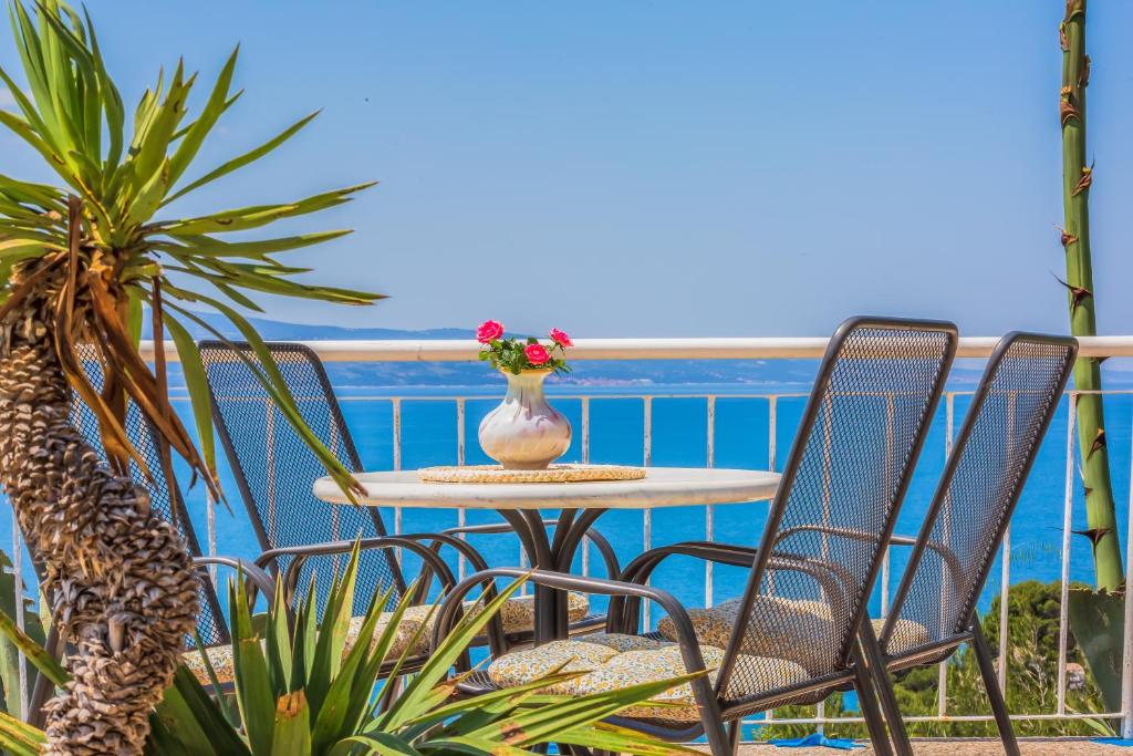 a table and chairs with a vase of flowers on a balcony at Blu Breeze Apartments in Lokva Rogoznica