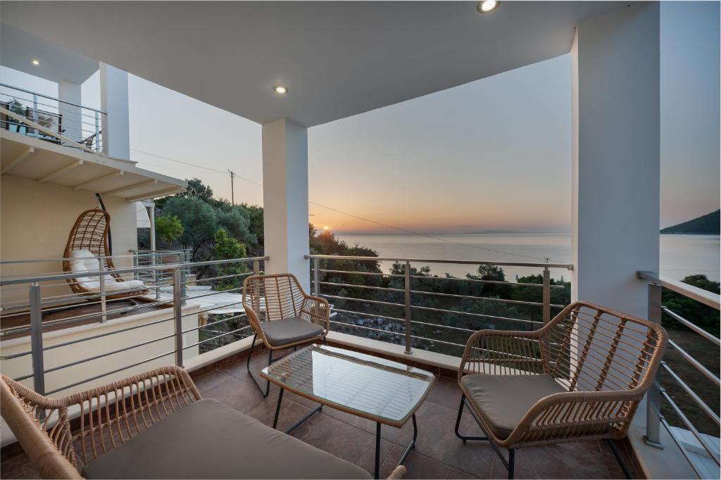 balcón con sillas, mesa y vistas al océano en Nikole's Villas Luxury 180m2, en Tyros