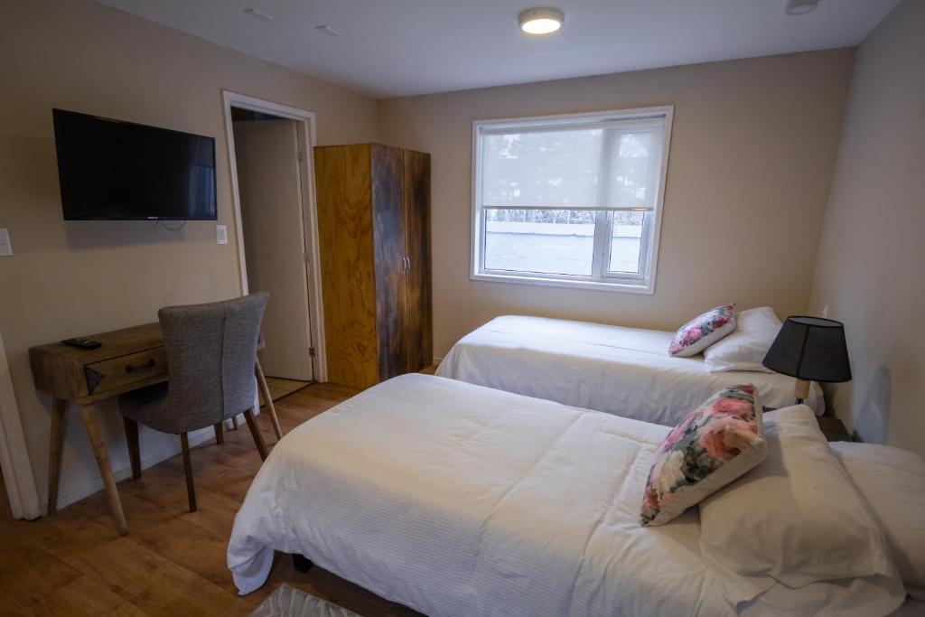 1 Schlafzimmer mit 2 Betten, einem Schreibtisch und einem TV in der Unterkunft Departamentos Avenida Colon in Punta Arenas
