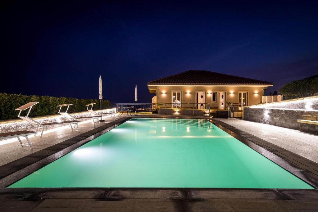 a swimming pool in front of a house at night at Affittacamere villa Antonio in Aci Castello