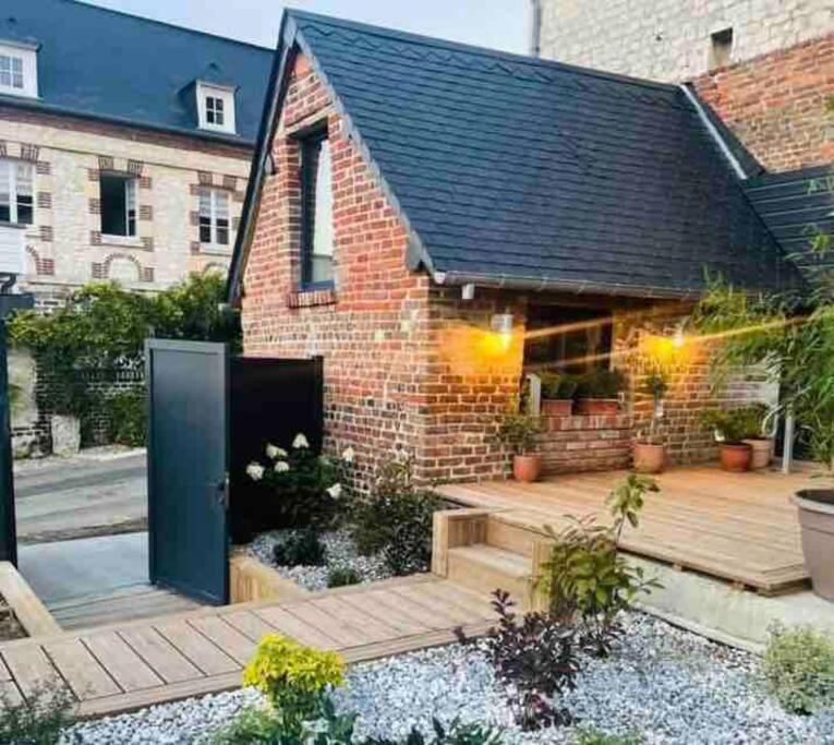 une arrière-cour avec une terrasse en bois et une maison en briques dans l'établissement la planque d'hugo, à Jumièges