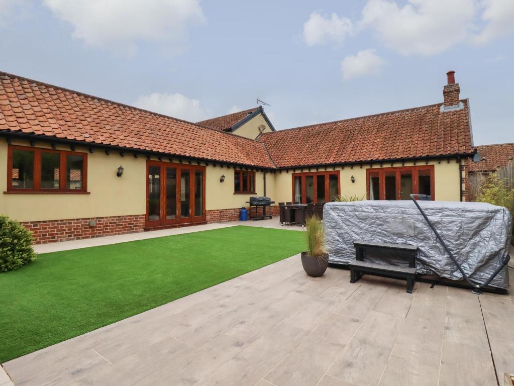 a house with a lawn with a blanket on it at The Stables at Hall Barn in Diss