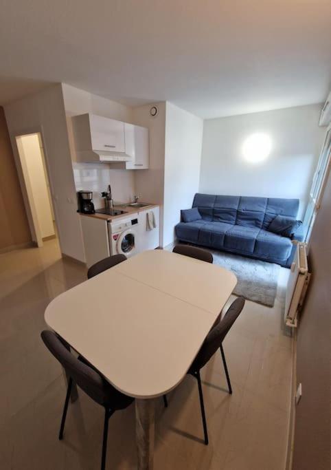 a room with a table and chairs and a couch at Résidence Du Grand Stade in Saint-Denis