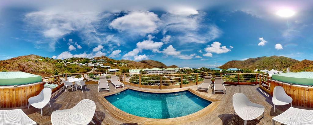 ein Resort mit einem Pool und Liegestühlen in der Unterkunft LES LAURIERS - PISCINE SUR LE TOIT - ANSE MARCEL in Anse Marcel 