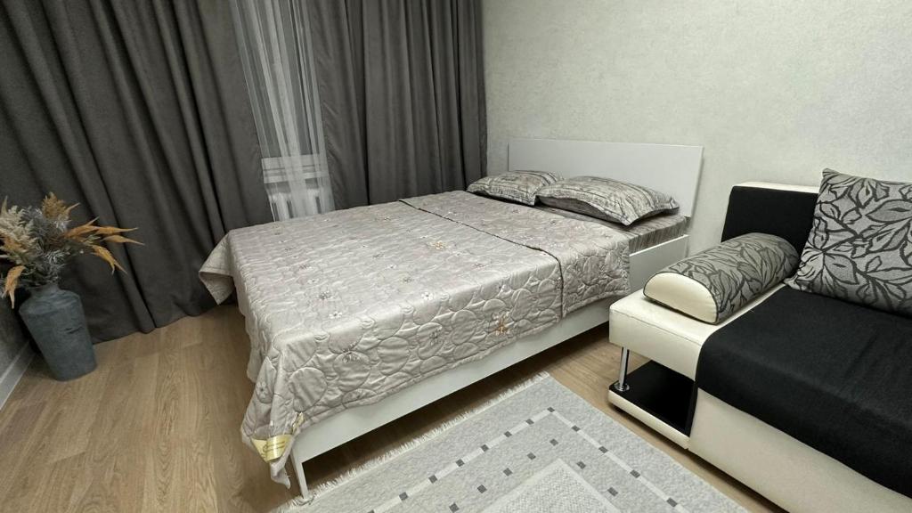 een kleine slaapkamer met een bed en een bank bij Квартира в микрорайоне Коктем 3 in Alma-Ata