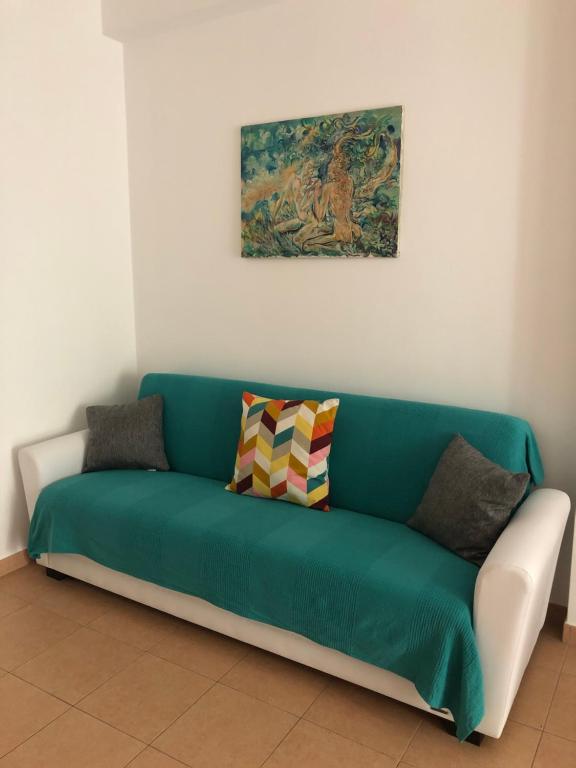 um sofá verde com almofadas num quarto em Alcantara Apartment em Gaggi