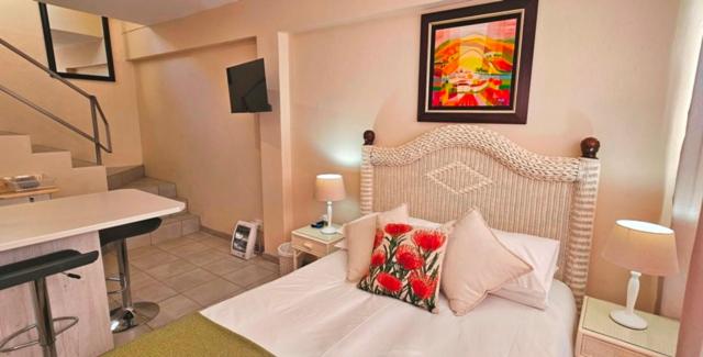 a bedroom with a white bed with two pillows on it at Sea la vie Self Catering Studio Apartment in Gordonʼs Bay