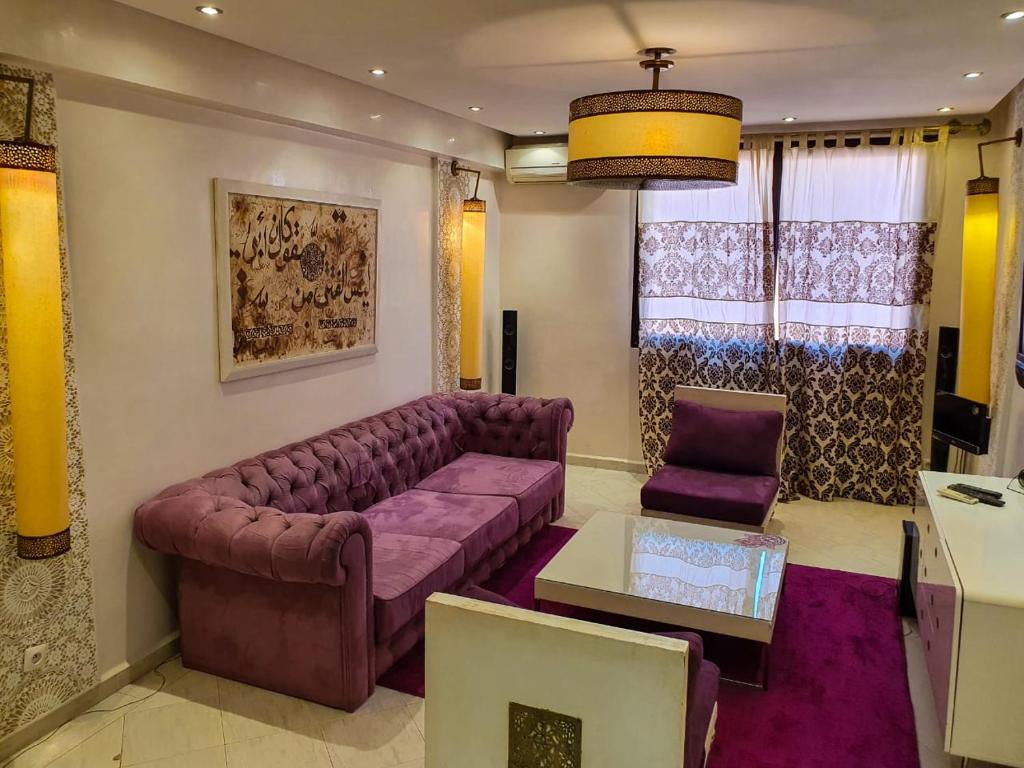 ein Wohnzimmer mit einem lila Sofa und einem Tisch in der Unterkunft Merzouga apartments in Merzouga