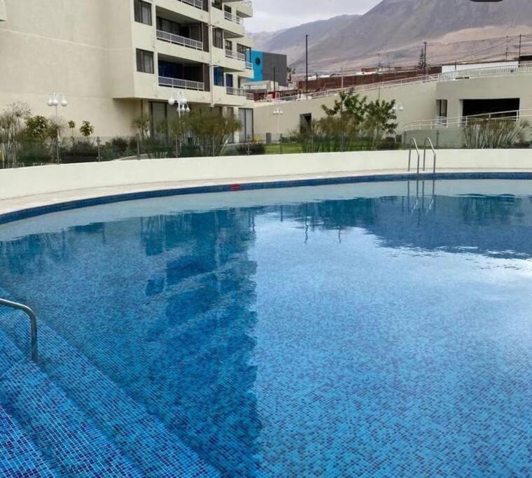 a large blue swimming pool in front of a building at Cómodo y Nuevo Depto. Amoblado in Iquique