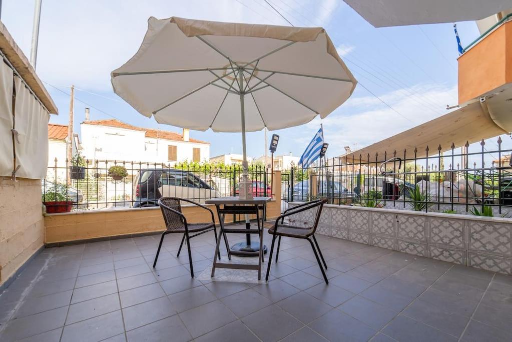 een tafel en stoelen met een parasol op een balkon bij Cleri's Studio in Néa Péramos